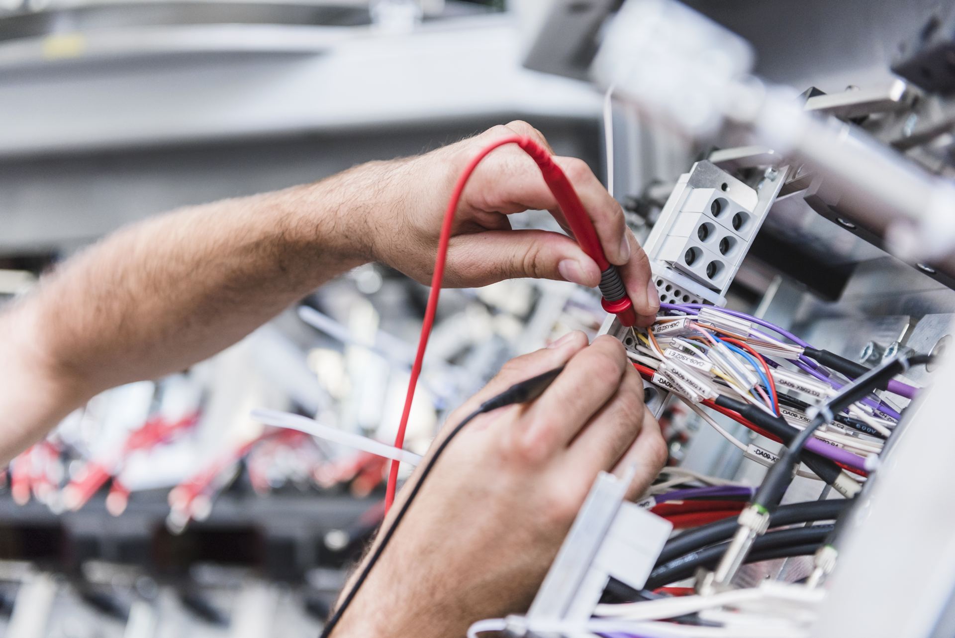 Electrician testing wiring in a distribution panel with a meter